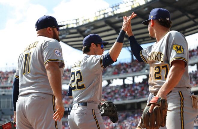 ATLANTA, GEORGIA - OCTOBER 11: Christian Yelich # 22 of Milwaukee Brewers High Fives Willy Adames # 27 during the second inning against the Atlanta Braves in Game 3 of the National League Division Series at Truist Park on October 11, 2021 in Atlanta, Georgia.  (Photo by Kevin C. Cox / Getty Images)