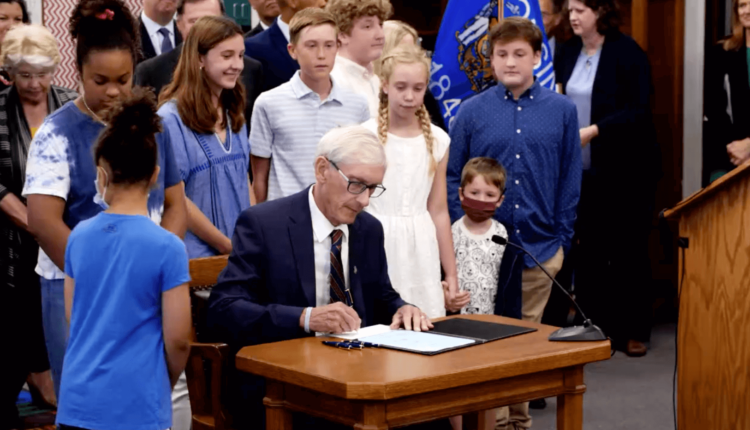 Gov. Tony Evers signs the 2021-23 biennial budget at Cumberland Elementary School in Whitefish Bay, after making 50 partial vetoes (screenshot 