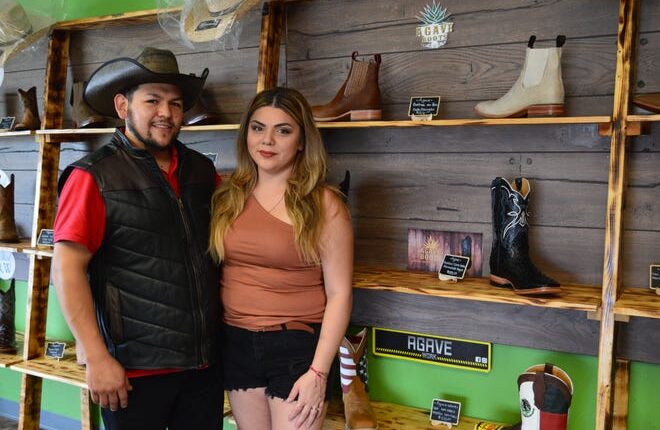 Owners Gerardo and Kaylee Sanchez, stand inside their western apparel shop in Green Bay.