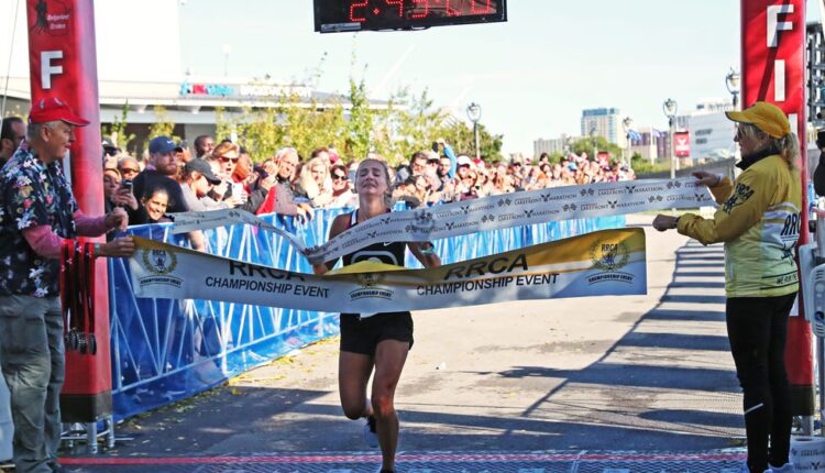 Women's top finisher Liz Berkholtz crosses the finish line at the 2019 Lakefront Marathon.