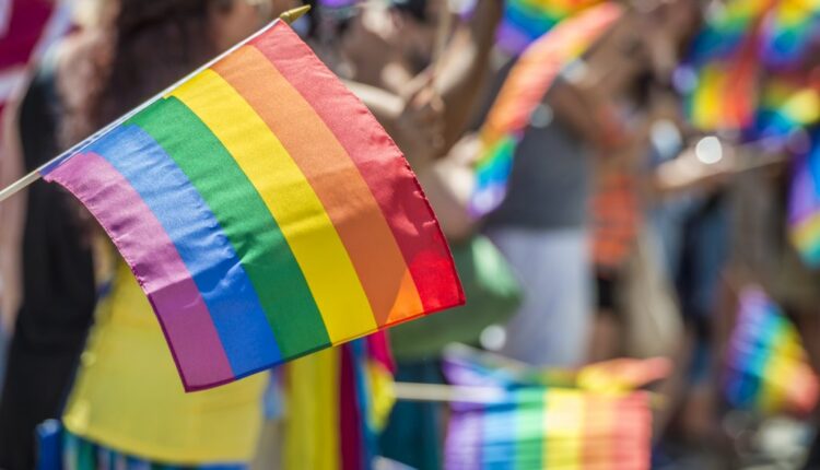 Close-Up of rainbow flag with crowd In background during LGBT Pride Parade. Getty Images.