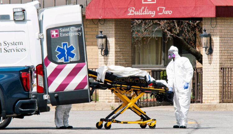 A photo from 2020 of medical workers loading a dead body into an ambulance while wearing masks and personal protective equipment at Andover Subacute and Rehabilitation Center in New Jersey.